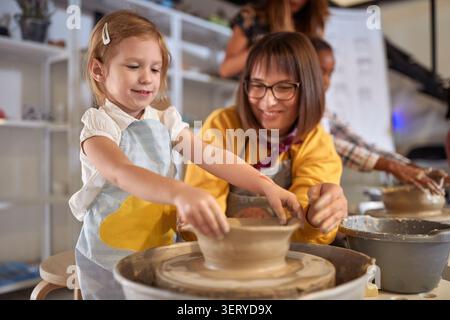 fille heureuse appréciant le processus de fabrication de pot fait à la main à l'atelier de poterie. Créatif, passe-temps, concept d'atelier Banque D'Images