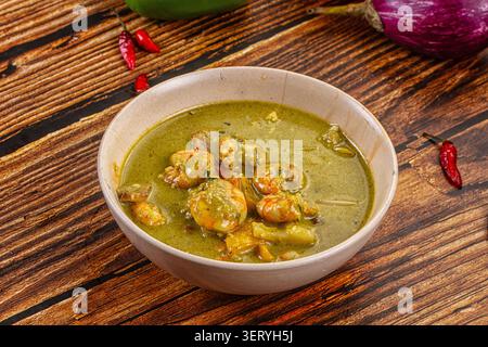 Curry vert éclatant avec de succulents légumes de crevettes servis dans un bol en céramique. La surface en bois rustique fournit un fond chaud. Points forts de la vue de dessus Banque D'Images