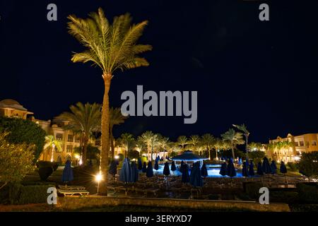 Nuit dans une station balnéaire égyptienne de la mer Rouge avec des palmiers et une piscine éclairée Banque D'Images