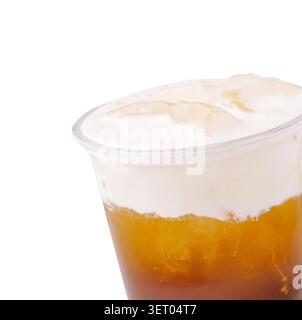 Thé en couches rafraîchissant et froid garni de crème salée. Boisson ambre glacée avec mousse de fromage dans une tasse en plastique. Banque D'Images