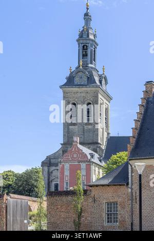 Le clocher de l'église historique d'Abdij van Park s'élève au-dessus des bâtiments en briques rouges à Louvain, en Belgique, encadrés par des arbres et un ciel bleu clair, mettant en évidence FL Banque D'Images
