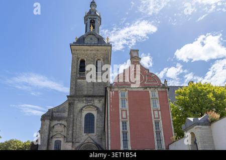 Le clocher de l'église historique d'Abdij van Park s'élève au-dessus des bâtiments en briques rouges à Louvain, en Belgique, encadrés par des arbres et un ciel bleu clair, mettant en évidence FL Banque D'Images