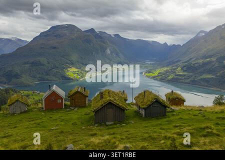 Vue aérienne de la ferme historique de montagne de Rakssetra avec des cabanes traditionnelles au toit en herbe surplombant le Nordfjord et les montagnes spectaculaires de Stryn Mun Banque D'Images