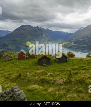 Vue aérienne de la ferme historique de montagne de Rakssetra avec des cabanes traditionnelles en bois au toit d'herbe surplombant les eaux bleues profondes du Nordfjord, Str Banque D'Images