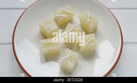 Gâteau de manioc ou cubes de gelée de noix de coco sur l'assiette. Dessert sucré thaïlandais traditionnel à base de pudding de manioc tapioca et de lait de coco garni de cocos Banque D'Images