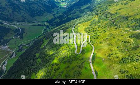 Vue aérienne d'une route de montagne sinueuse à travers la vallée verdoyante dans la région des Alpes autrichiennes Banque D'Images