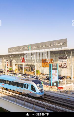 Dubaï, Émirats arabes Unis - 25 octobre 2025 : train moderne sans conducteur sur la voie surélevée du métro de Dubaï. Entrée du centre commercial Dubai Times Square Center, façade vitrée et Banque D'Images