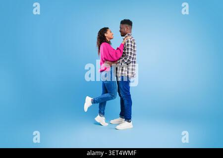 Heureux jeune couple embrassant et souriant ensemble, fond de studio, concept d'amour Banque D'Images