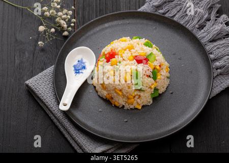 Riz frit doré moulé sur assiette avec légumes et cuillère Banque D'Images