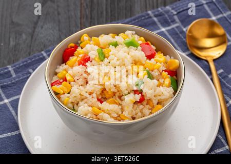 Riz frit doré moulé sur assiette avec légumes et cuillère Banque D'Images