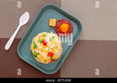 Riz frit doré moulé sur assiette avec légumes et cuillère Banque D'Images