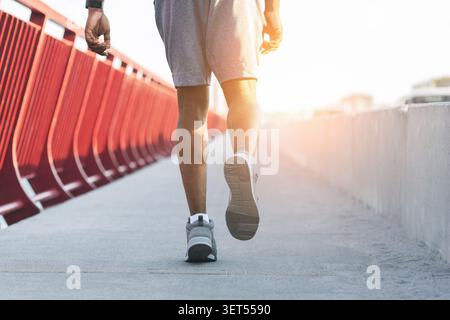 Image recadrée d'un homme africain sportif courant sur un pont Banque D'Images