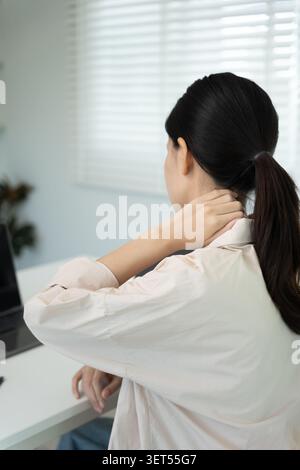 syndromes de bureau, femme massant des douleurs cervicales dues au travail et à l'aide d'un ordinateur, composite numérique d'une colonne vertébrale focalisée de douleurs cervicales et d'épaule symp Banque D'Images