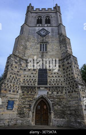 Vue de face de la tour historique de l'église à l'abbaye de Waltham, Essex, montrant l'architecture gothique, le cadran de l'horloge et la porte voûtée sous un ciel bleu. Banque D'Images