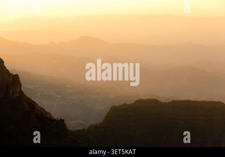 Un coucher de soleil doré brumeux à couper le souffle projetant des silhouettes superposées à travers les pics accidentés et les vallées des montagnes Simien., Éthiopie. Banque D'Images