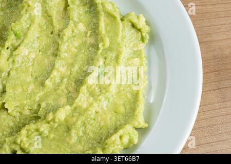 Sauce guacamole fraîche maison servie sur une assiette en céramique blanche, vue de dessus espace copie. Banque D'Images