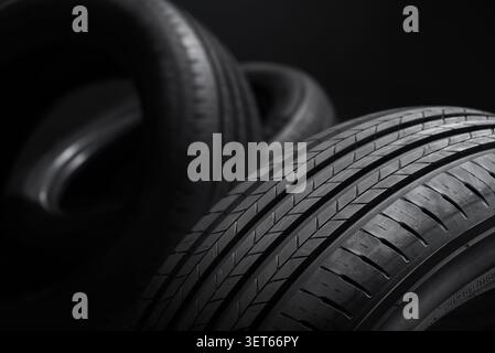 Pneus de voiture sur un fond sombre. Vue rapprochée de la bande de roulement d'un pneu d'été neuf. Banque D'Images