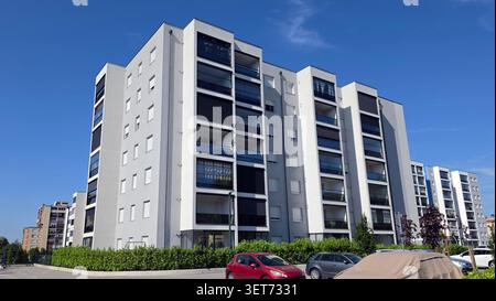 Vue panoramique sur un complexe résidentiel contemporain avec façades en plâtre blanc et balcons vitrés avec parasols sombres Banque D'Images