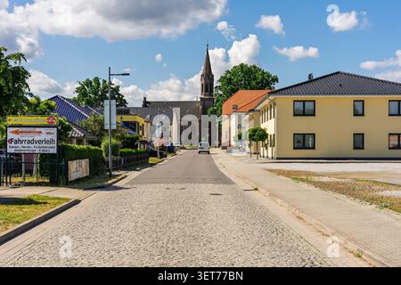 SENFTENBERG, ALLEMAGNE - 6 JUIN 2026 : vue sur la rue dans le quartier de Grosskoschen avec tour de l'église et panneau de location de vélos. Banque D'Images