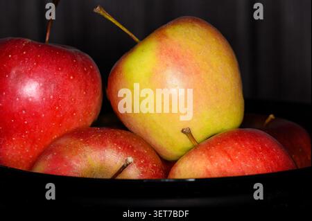 Un groupe de pommes repose dans un bol. Les pommes montrent un mélange de couleurs rouge et verte. Ils sont placés ensemble avec certains empilés sur d'autres Banque D'Images