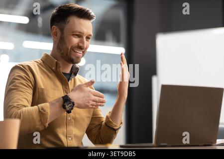 Joyeux jeune homme caucasien appel vidéo au bureau, interagir avec des collègues Banque D'Images