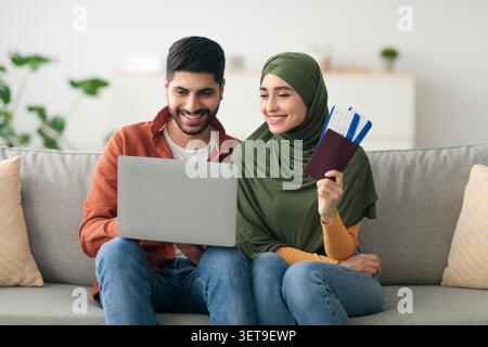 Heureux jeune couple travaillant ensemble sur ordinateur portable, planifier voyage, cadre de la maison Banque D'Images