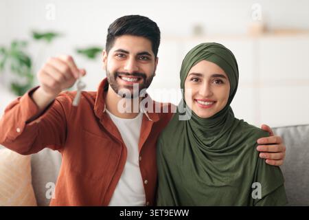 Heureux jeune couple tenant des clés de maison ensemble dans le salon, Nouveau concept de maison Banque D'Images