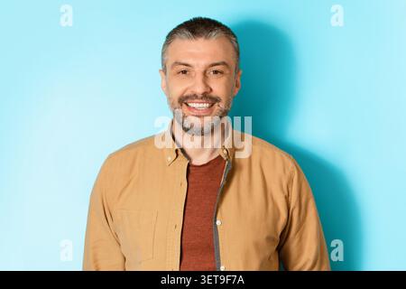 Homme caucasien souriant avec barbe debout sur fond bleu, concept d'affaires Banque D'Images