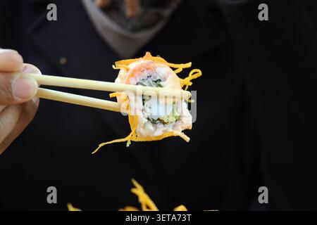Dégustez des rouleaux de sushi avec des baguettes dans un restaurant Banque D'Images
