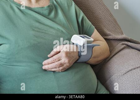 Femme âgée utilisant un moniteur de poignet numérique pour la mesure de la pression artérielle en gros plan Banque D'Images