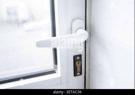 Poignée de porte en plastique blanc, close-up la porte a une fenêtre. Serrure, porte en plastique, bronze. Gros plan d'une porte. Banque D'Images