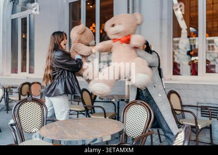 Amis Teddy Bears café patio s'amuser et jeter des jouets géants en peluche à l'extérieur pendant un après-midi ludique dans la ville Banque D'Images