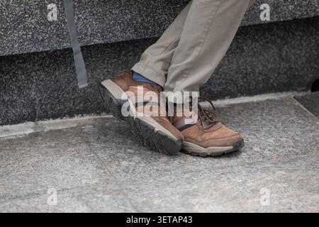 Homme en baskets brunes au repos, jambes croisées, vue en angle élevé Banque D'Images