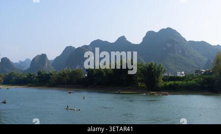 Pêcheurs sur des radeaux de bambou au-dessous d'une gamme de pics karstiques sur la rivière Li, Yangshuo, Guangxi, Chine Banque D'Images