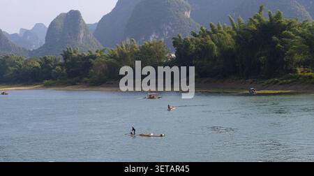 Les pêcheurs sur des radeaux de bambou descendent la rivière Li sous les montagnes karstiques brumeuses près de Yangshuo, Guangxi, Chine Banque D'Images