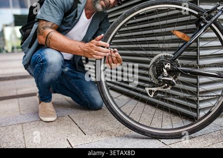 Homme fixant la roue de bicyclette à l'extérieur. Banque D'Images