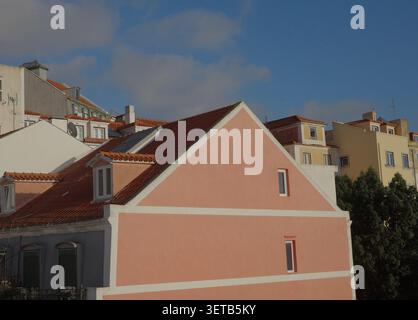 Bâtiments colorés de couleur pastel avec des toits en terre cuite sur Lisbonne Hillside, Maison à pignon rose en premier plan contre Blue Sky Banque D'Images