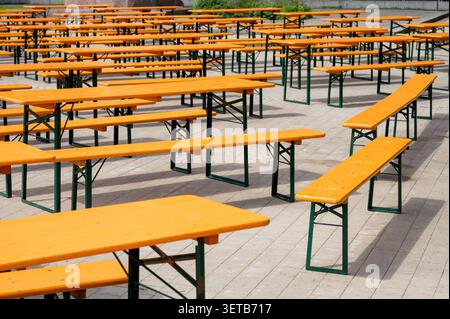 Rangées de tables pliantes en bois orange vides et de bancs pour un événement extérieur Banque D'Images