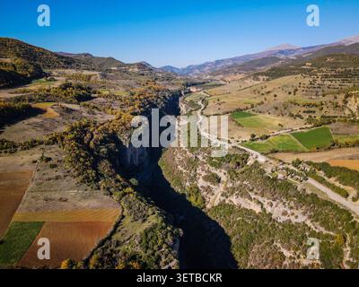 Une prise de vue aérienne par drone capture un canyon profond bordé d'arbres traversant un paysage rural avec une route sinueuse le long de celui-ci. Autour du canyon sont Banque D'Images