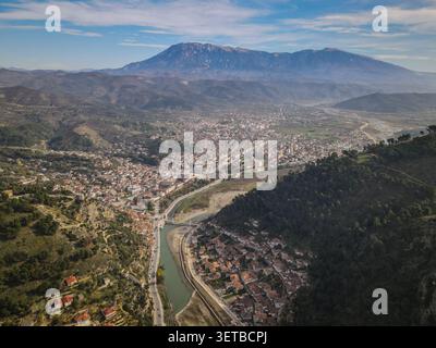 Une vue aérienne large capture la ville historique de Berat, en Albanie, nichée le long de la rivière Osum, avec ses maisons blanches caractéristiques de l'époque ottomane en escalade Banque D'Images