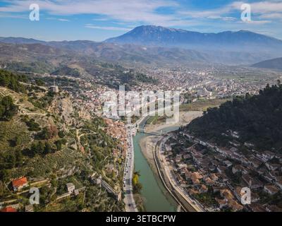 Une vue aérienne large capture la ville historique de Berat, en Albanie, nichée entre des collines verdoyantes et la rivière Osum sinueuse. L'OT blanc de la ville Banque D'Images