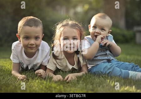 Trois enfants heureux se relaxant sur l'herbe Banque D'Images