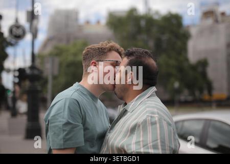 Couple gay partageant un baiser romantique dehors Banque D'Images