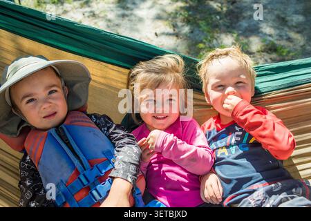 Trois enfants heureux se reposant ensemble dans un hamac Banque D'Images