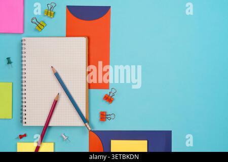 Concept de retour à l'école avec des crayons de carnet et de la papeterie colorée sur fond bleu Banque D'Images