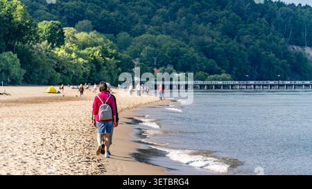 Couple senior marchant le long de la plage de la mer Baltique avec des sacs à dos le jour ensoleillé Banque D'Images