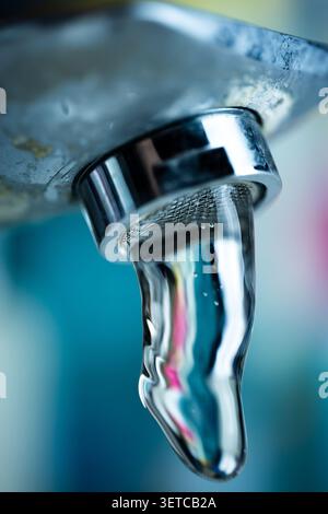 L'eau coule vers le bas d'un robinet chromé dans un évier de salle de bain Banque D'Images