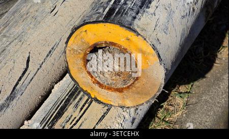 Une vue rapprochée montre un segment de pipeline coupé présentant une couche d'isolation jaune en acier rouillé fortement bloquée et une enveloppe extérieure noire rayée Banque D'Images