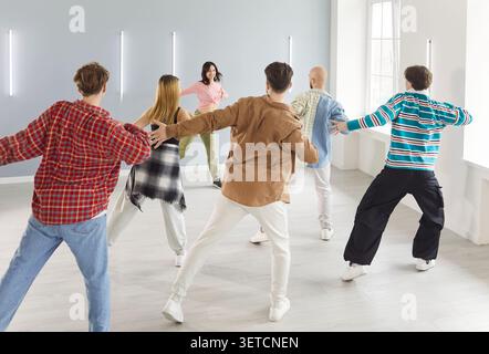 Groupe de danse de personnes dansant activement à l'intérieur, se déplaçant avec un entraîneur en classe Banque D'Images