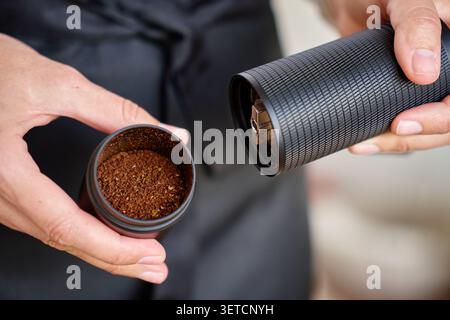 Les mains tiennent un moulin manuel ouvert avec du café moulu à l'intérieur. Concept de préparation du café et préparation manuelle. Banque D'Images